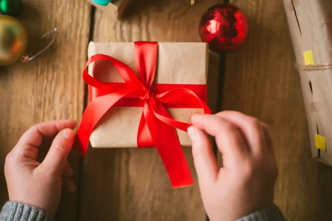 Woman wrapping christmas gifts on wooden background