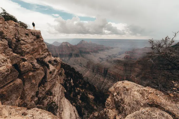 Young woman overlooking Grand Canyon while a thunderstorm approaches