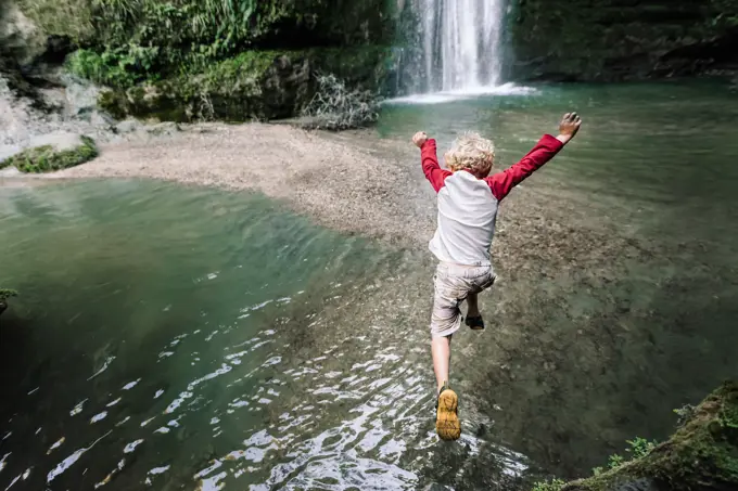 View from above of preschooler jumping into water in New Zealand