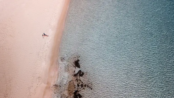 a woman alone on a beach with a clear blue water in Greece