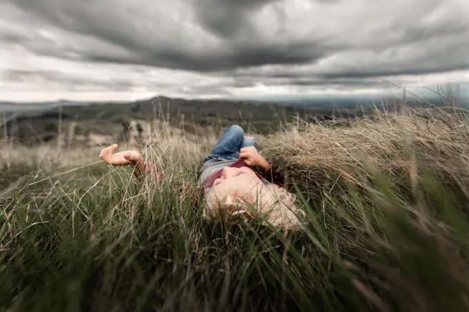 Young boy lying in tall grass