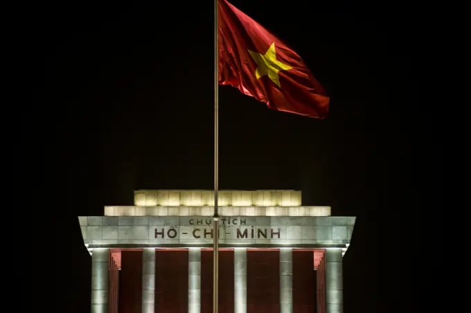 Ho Chi Minh mausoleum at night and Vietnam flag fluttering in the wind