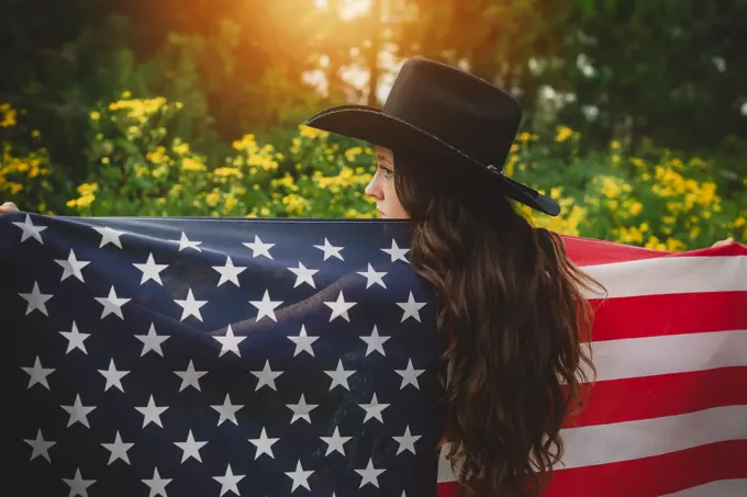 Young teen in cowboy hat holding American Flag