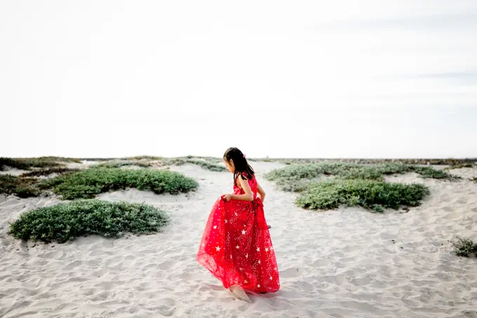 Six Year Old Asian Girl in Red Dress Walking on Beach