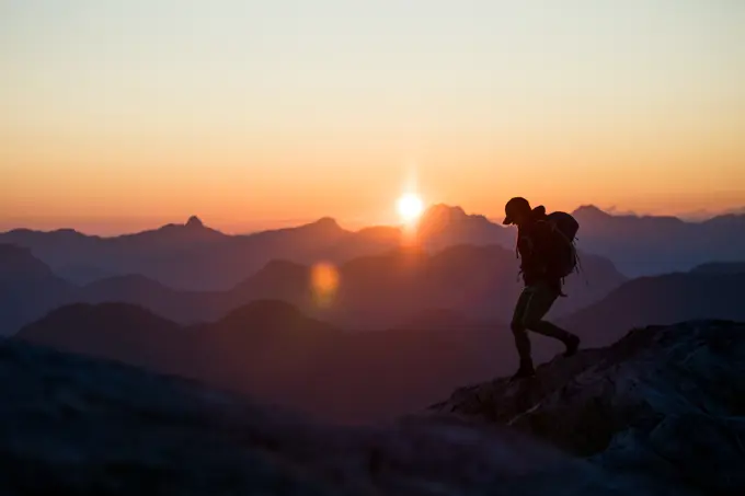 Silhouetted view of fit healthy woman running on mountain summit