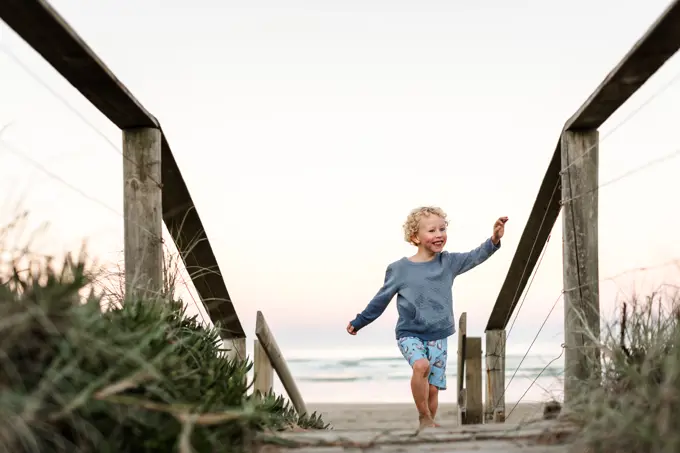 Happy boy on boardwalk at beach in New Zealand