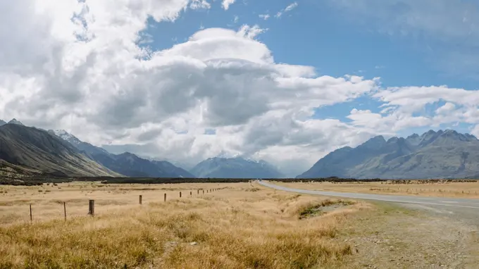 Rural road winds through grazing land and mountains in NZ countryside