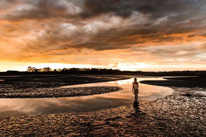 Girl watching beautiful sunset at an estuary in New Zealand