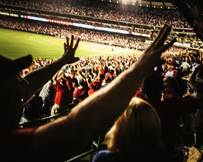 Baseball fans raising their arms.