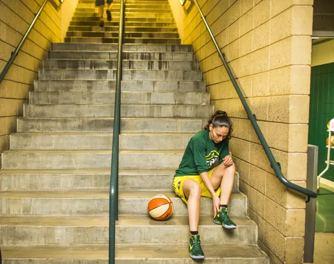 Female basketball player sitting on steps and preparing for game, Seattle, Washington, USA