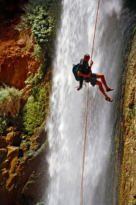 A man rappelling next to a waterfall, Grand Canyon, Arizona.