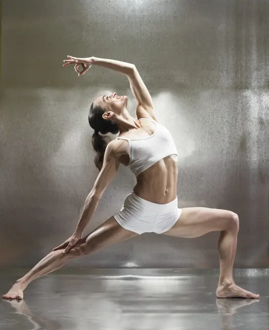 A caucasian female performs yoga in a studio