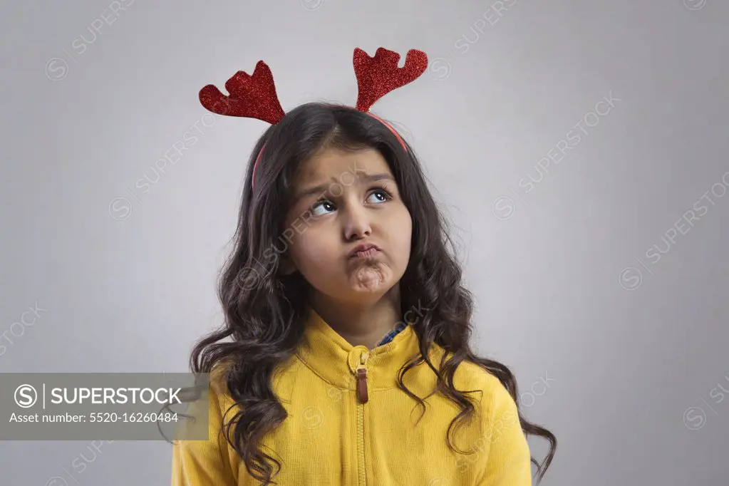 Portrait of a young girl  wearing a reindeer antlers headband. (Christmas)