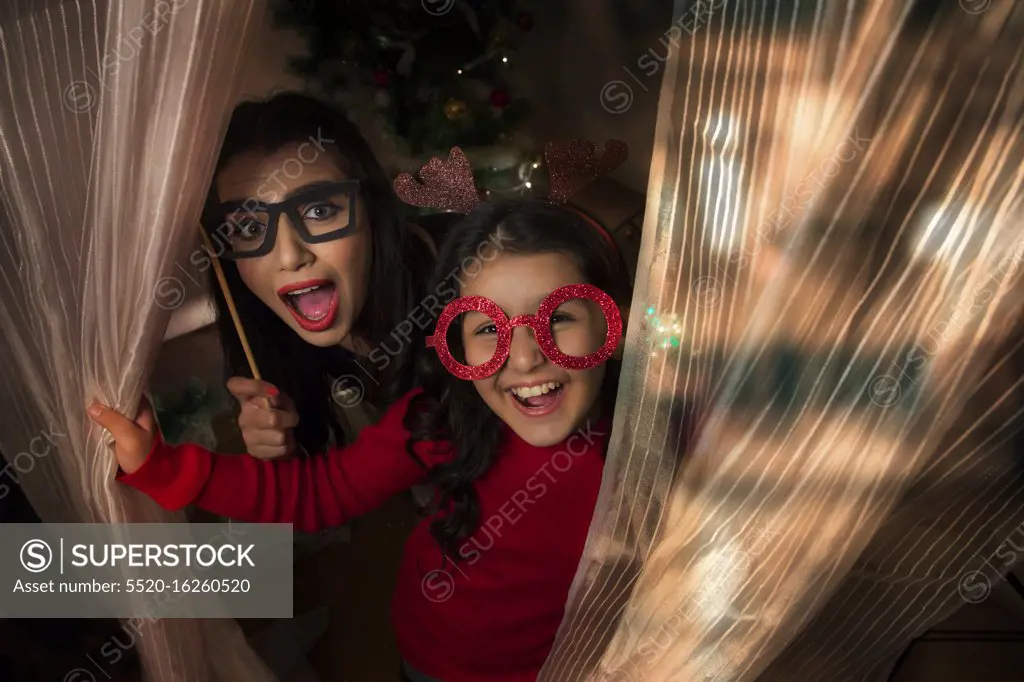 Portrait of a mother and daughter wearing antlers and and eye mask props during Christmas.