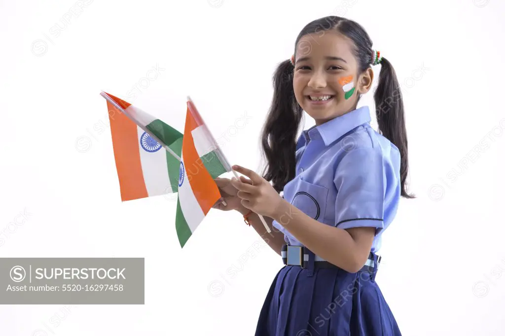 young school girl with flag drawn on her cheeks and holding flags in her hand , independence day