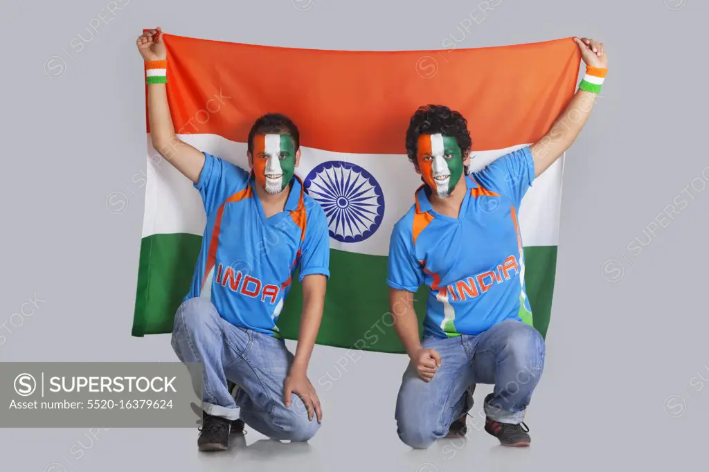 Two male friends with face painted in a tricolor holding Indian flag over colored background