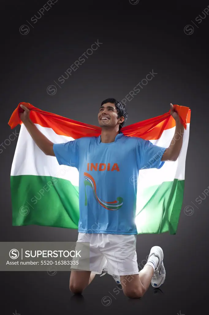 Hockey player looking up as he holds Indian flag with pride against black background, INDEPENDENCE DAY