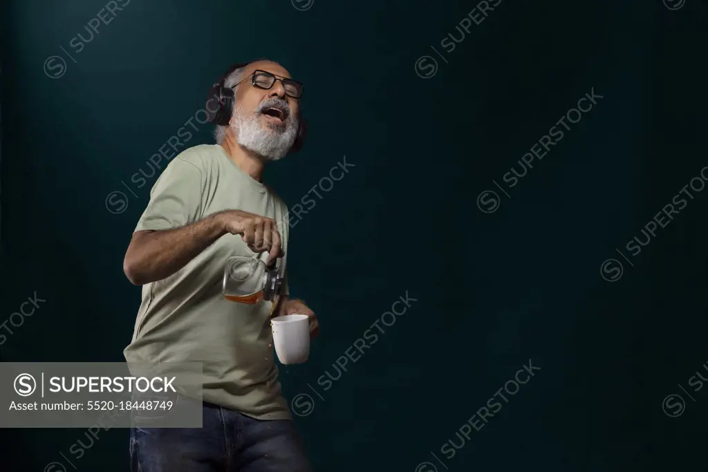 A HAPPY OLD MAN SPILLING COFFEE WHILE DANCING TO MUSIC