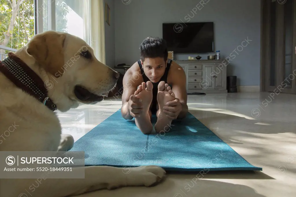 Man doing yoga exercises and his dog sitting with him. 