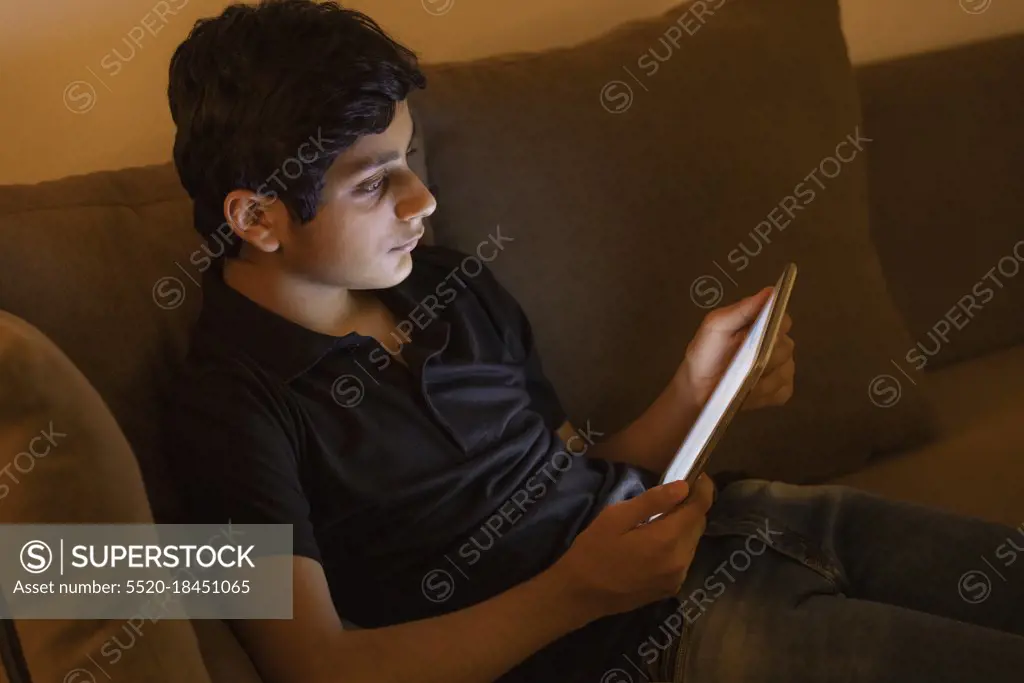 A TEENAGER USING DIGITAL TABLET WITH CONCENTRATION