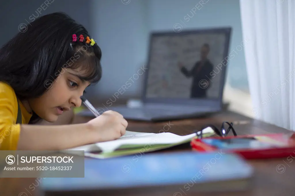 Young girl doing her work while attending virtual class