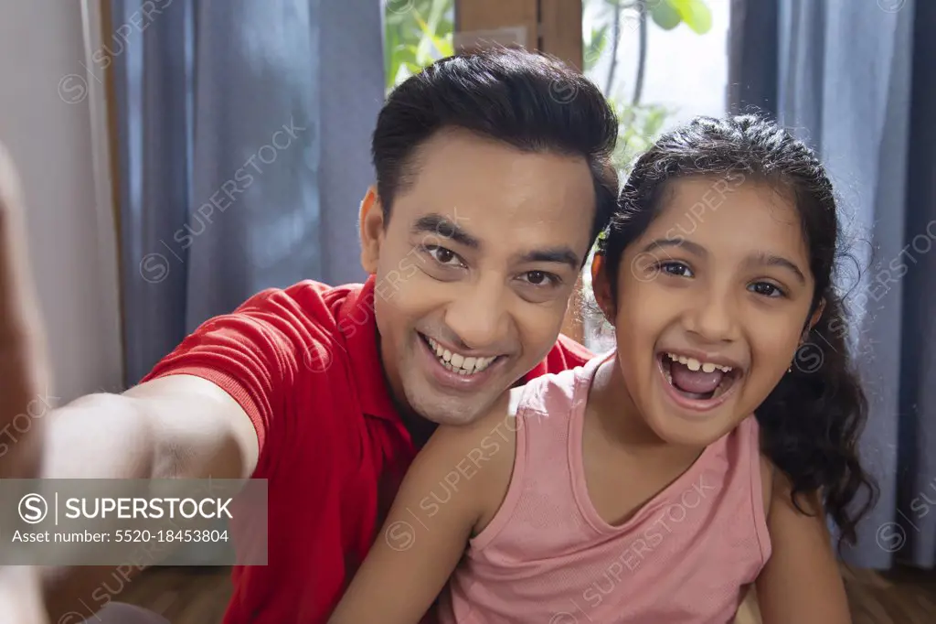 Father and daughter enjoying at home Taking selfies with smart phone