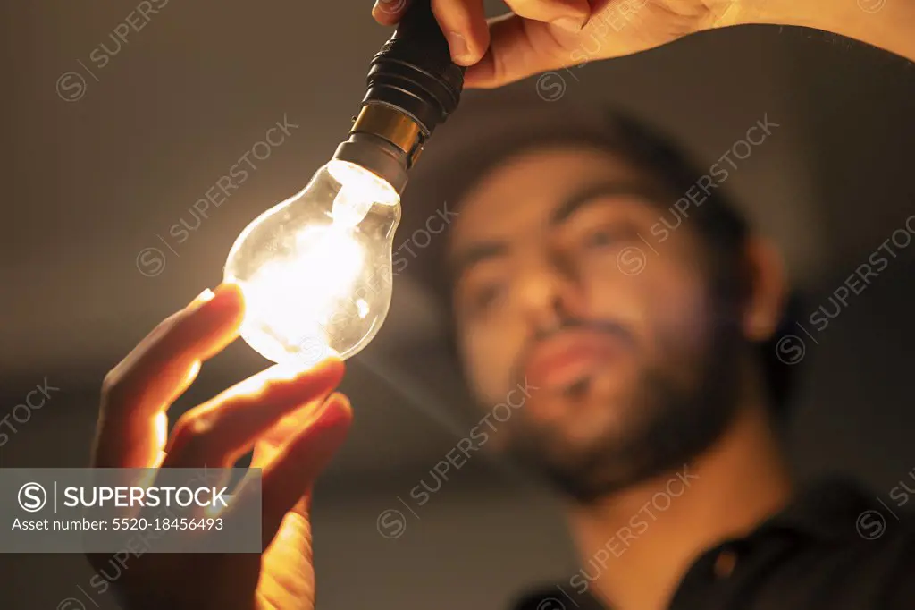 AN ELECTRICIAN HOLDING A WELL LIT ELECTRIC BULB