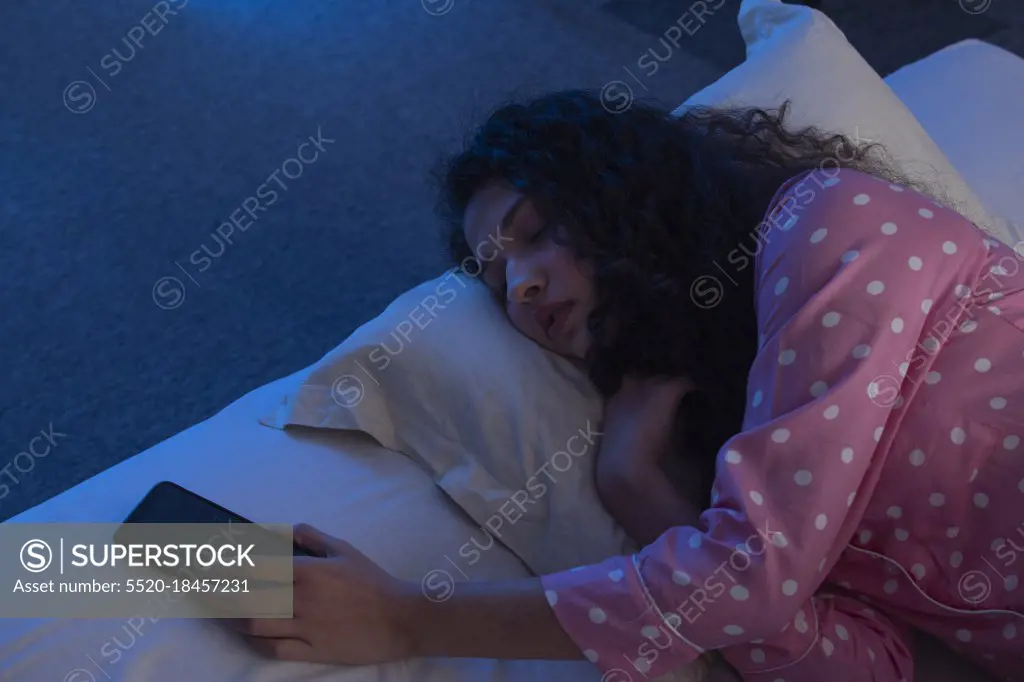 A TEENAGE GIRL SLEEPING WITH PHONE IN HAND