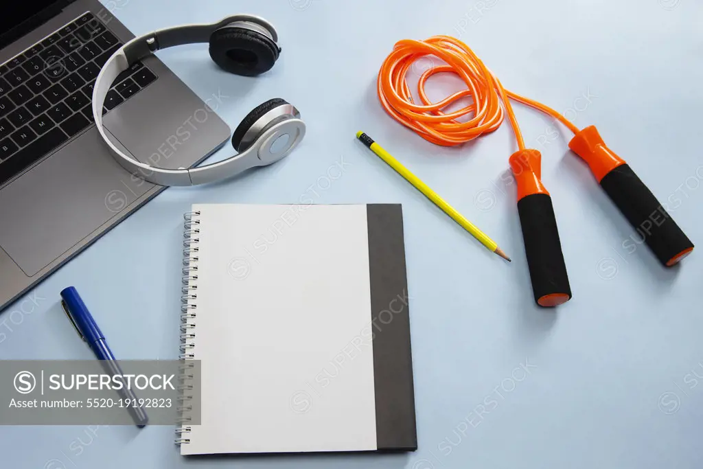 A notepad skipping rope pencil pen headphones and laptop kept