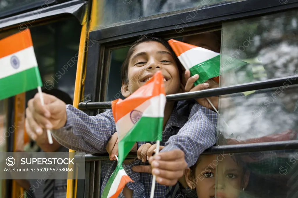 School boys holding the Indian flag in a bus