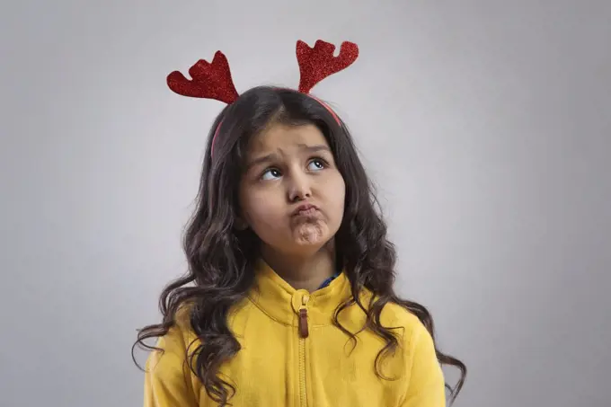 Portrait of a young girl  wearing a reindeer antlers headband. (Christmas)