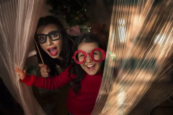 Portrait of a mother and daughter wearing antlers and and eye mask props during Christmas.