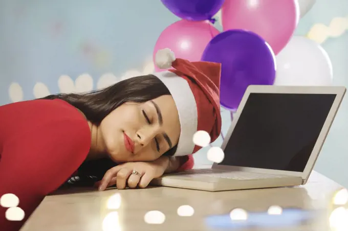 Young woman asleep on her desk after office party.