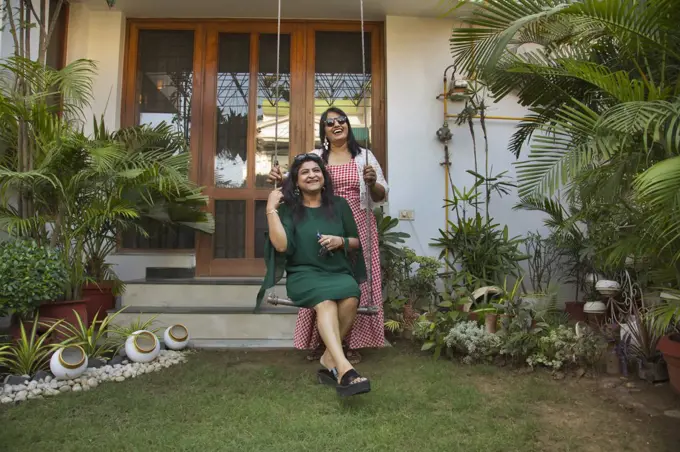 Women standing near a swing in the backyard and enjoying together.