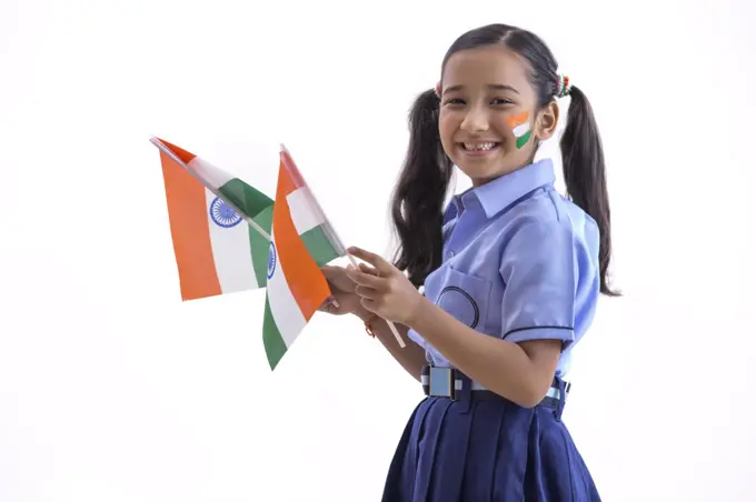 young school girl with flag drawn on her cheeks and holding flags in her hand , independence day