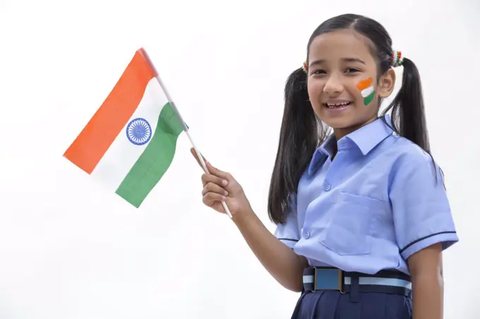 young school girl with flag drawn on her cheeks and holding flag in her hand , independence day