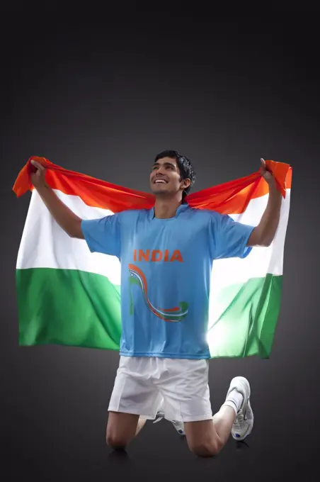 Hockey player looking up as he holds Indian flag with pride against black background, INDEPENDENCE DAY