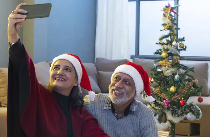 A HAPPY OLD COUPLE CLICKING SELFIE AFTER DECORATING CHRISTMAS TREE