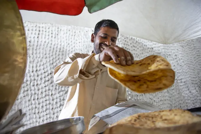 Male vendor selling paratha at his roadside food stall