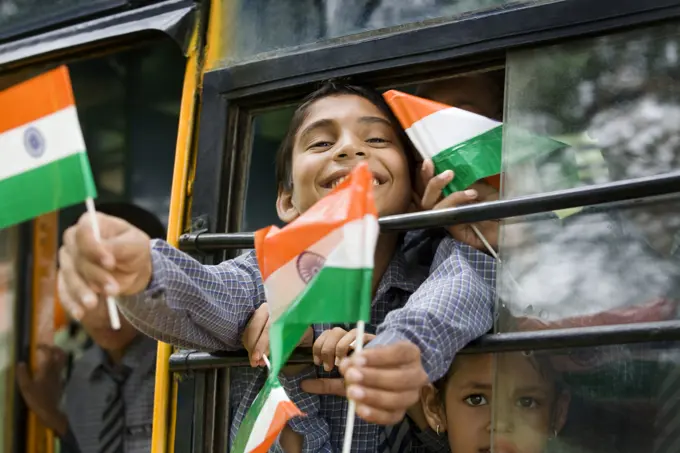 School boys holding the Indian flag in a bus