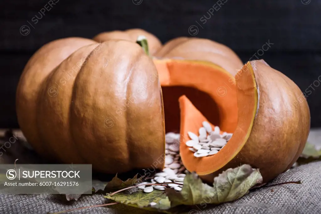 pumpkin lying on a wooden table with viburnum and seeds