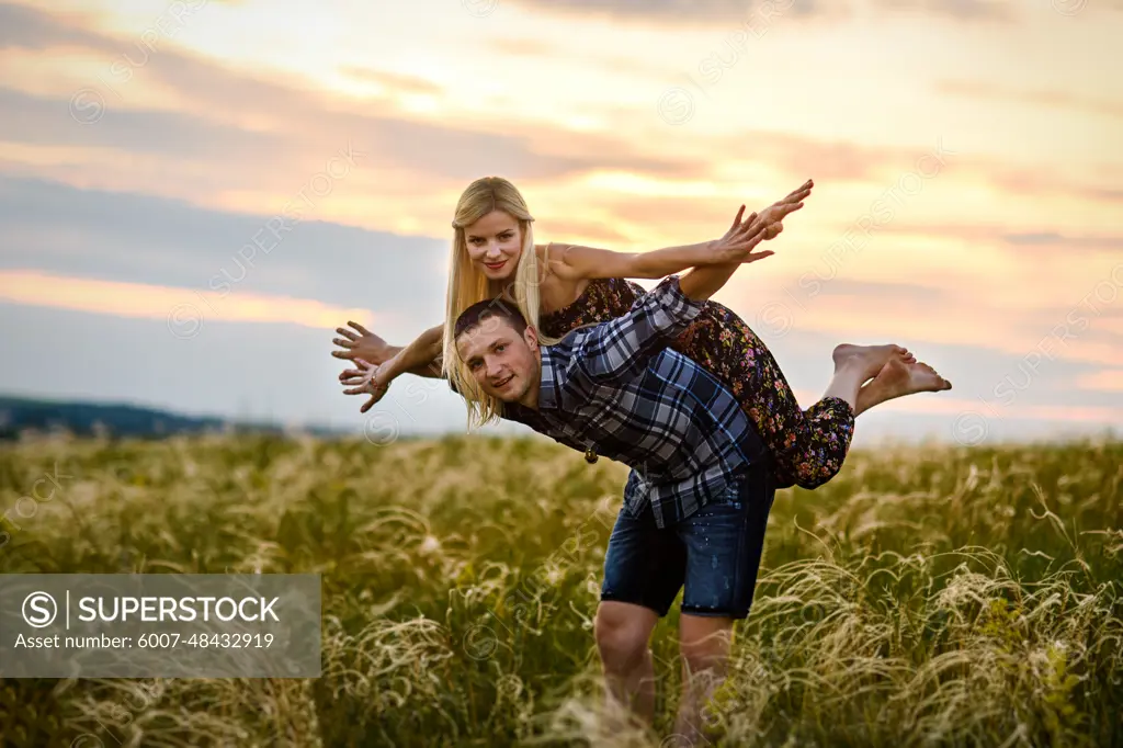 couple in love blonde girl and guy in the grass at sunset