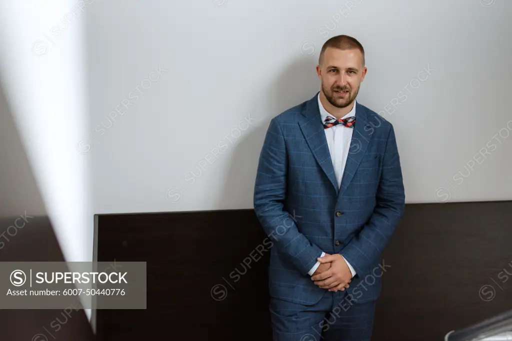 portrait of smiling groom with beard in blue color suit