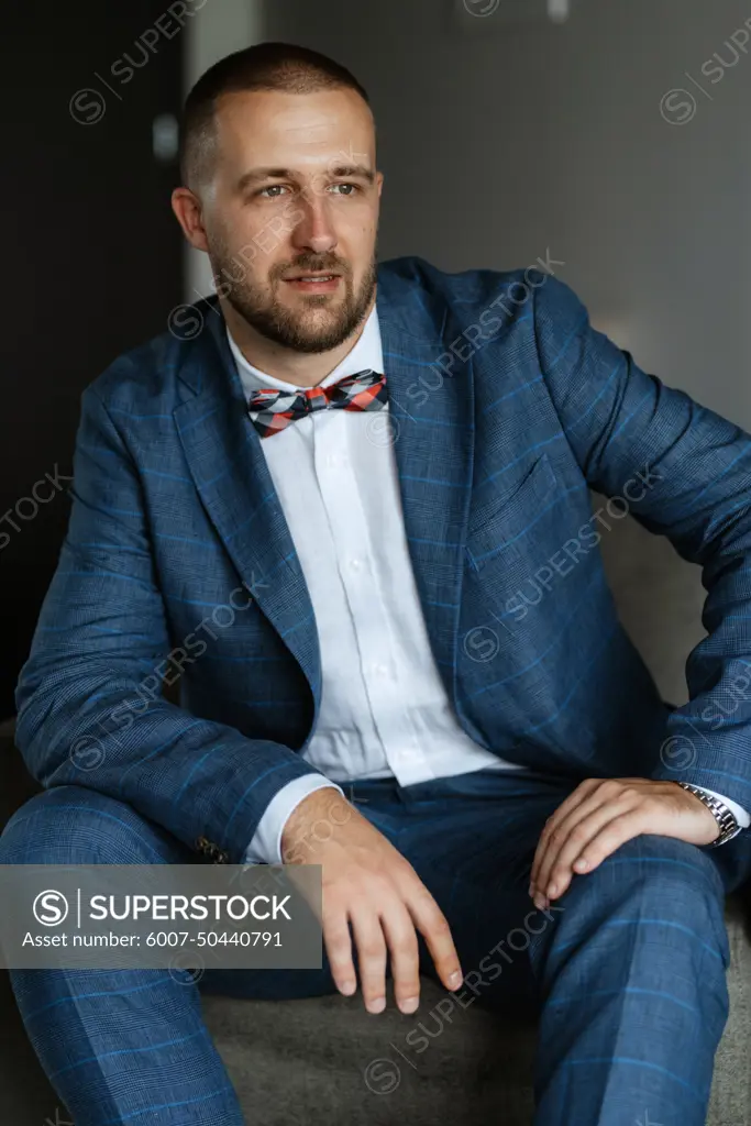 portrait of smiling groom with beard in blue color suit