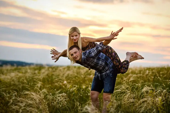 couple in love blonde girl and guy in the grass at sunset