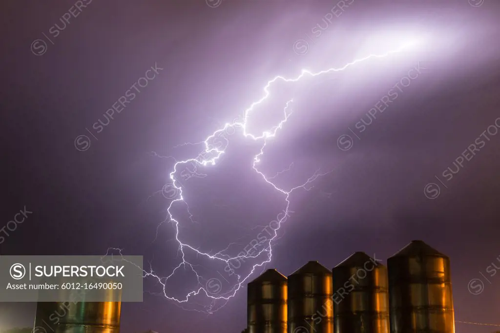 A storm passes over large metal containers releasing electrical charge