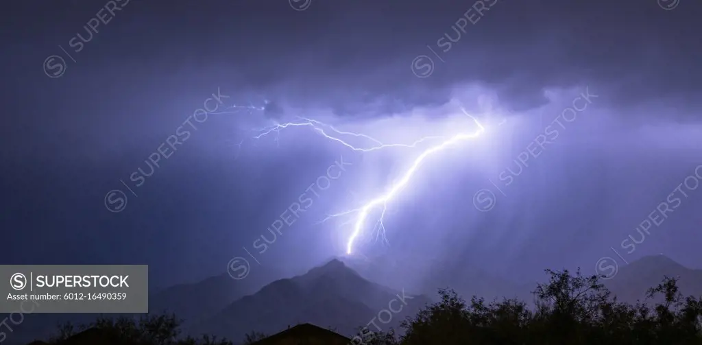 Summer electrical storm produces a lightning bolt illuminating a valley in rural Arizona