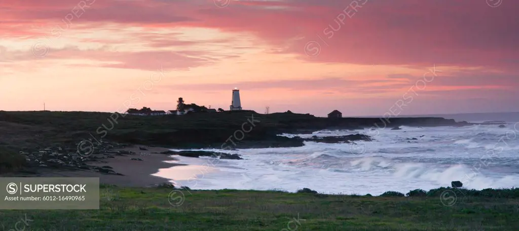 The lighthouse shines light out to the sea at sunrise