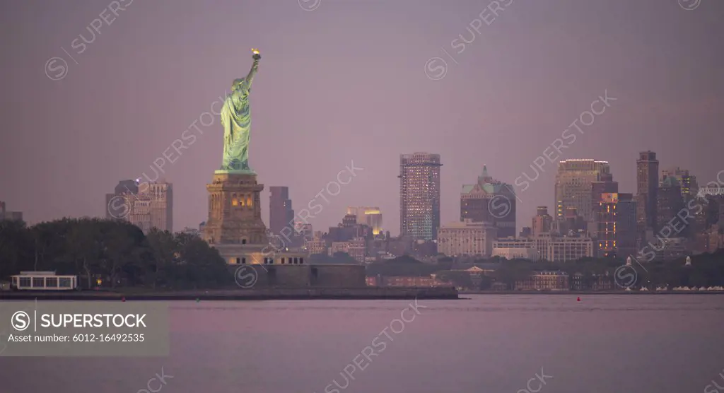 The Statue of Liberty after sunset with Brooklyn New York in the background