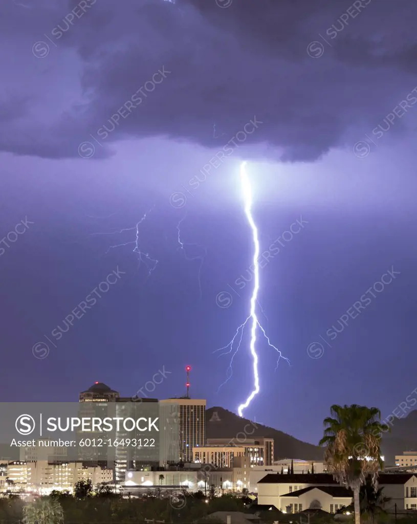 Purple Blue light illuminates the sky over the buildings homes and hills around Tucson Arizona